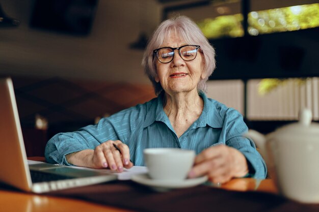 Elderly woman working in front of laptop monitor sitting Retired woman chatting unaltered