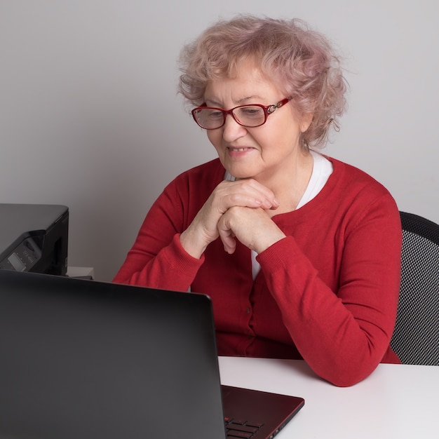 Una donna anziana che lavora con il computer portatile sopra la tavola bianca.