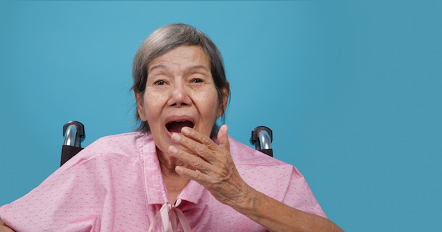 Elderly woman yawning on wheelchair