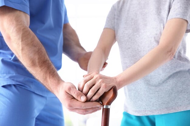 Photo elderly woman and young man holding hands on walking stick closeup physiotherapy concept