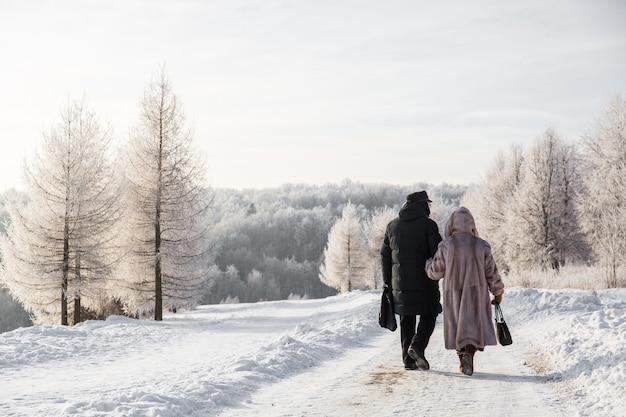 Eldery couple walking in white winter forest. Beautiful landscape. People in the forest