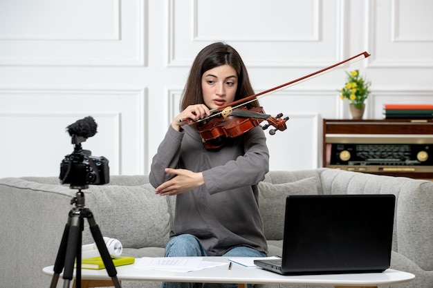 Elearning cute young beautiful girl remotely at home taking violin classes on laptop