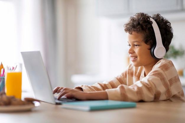 행복한 흑인 학생이 집에서 노트북으로 온라인으로 공부하고 있습니다.