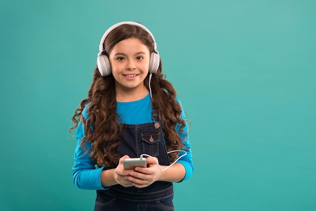 Elearning in het moderne leven schoolmeisje gebruik nieuwe technologie kopieer ruimte kind luister muziek in koptelefoon klein kind maakt afspeellijst op smartphone klein meisje houdt mp3-speler vast die favoriet nummer kiest