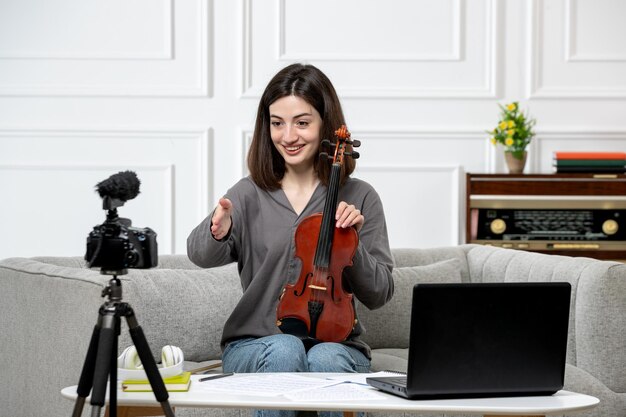 Elearning remotely giving violin classes at home young cute beautiful girl very happy on camera