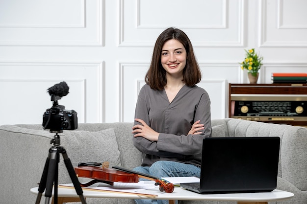 Elearning giovane bella ragazza carina a distanza a casa dando lezioni di violino seduto con sicurezza