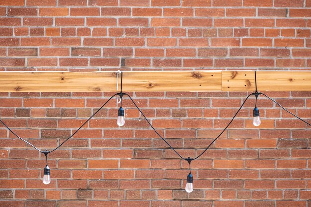 Electric bulbs with wire on red brick wall background