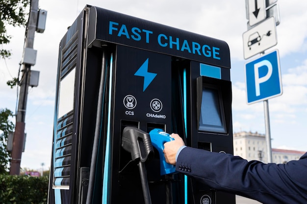 An electric car battery charging station on a city street A modern gas station with electricity businessman charges an electric car