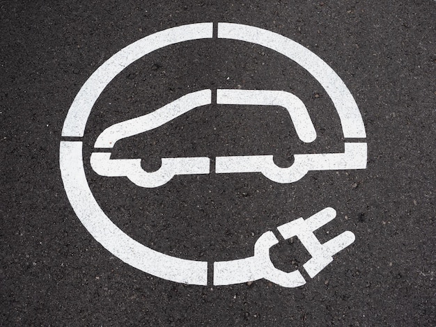 electric car charger symbol painted in white on the road asphalt