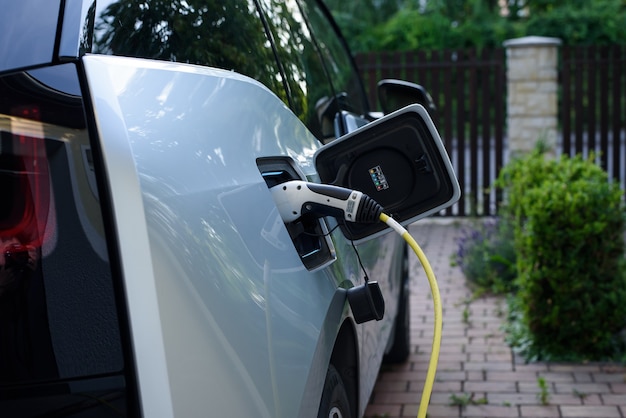 Electric car charging station power supply joined to modern\
electric car being charged