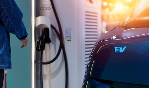 Ricarica per auto elettriche con uomo della stazione che collega un cavo di ricarica a un'auto da una stazione di ricarica per auto elettriche