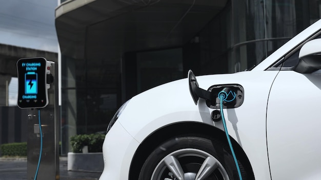 Electric car connected to charging station at city center Peruse