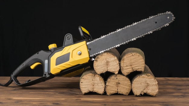 Electric chain saw on sawn logs on a black background. Electric tool for wood processing.