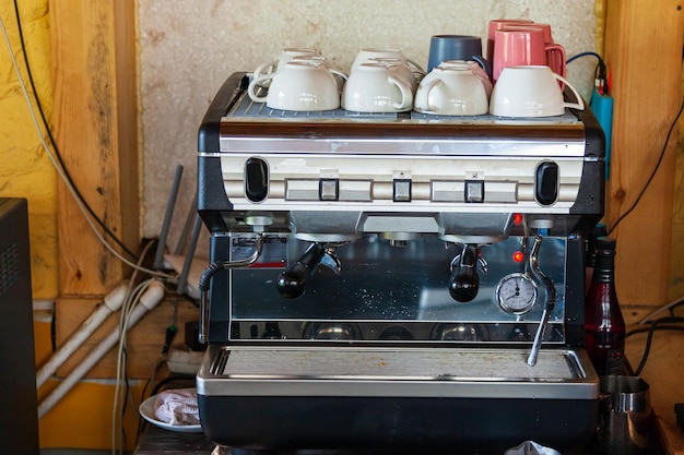 Electric coffee machine with mugs on top in a bar or cafe for making delicious drinks