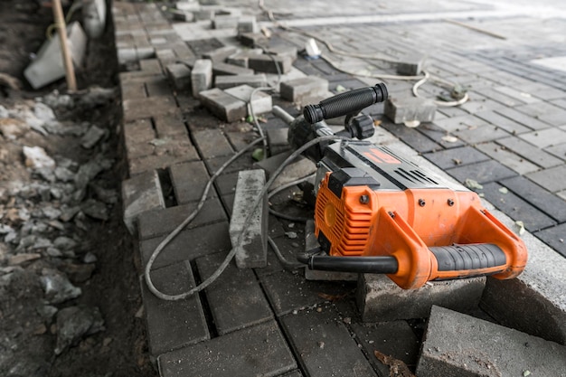 Photo electric concrete breaker laying on a road of cobblestone during sidewalk construction works