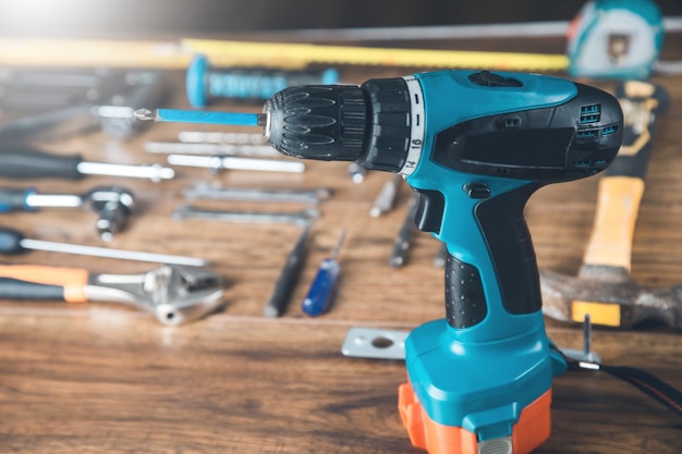 Electric drill with tools on the wooden table