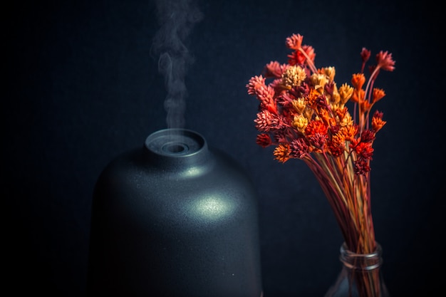 Foto oli essenziali elettrici diffusore di aromi e fiori sul tavolo di legno