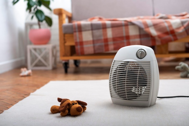 Electric fan heater on the floor in living room with human sitting on the sofa at background