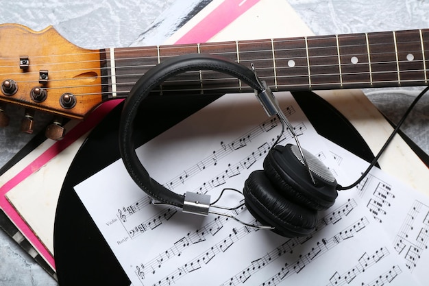 electric guitar and headphones with music notes on grey background