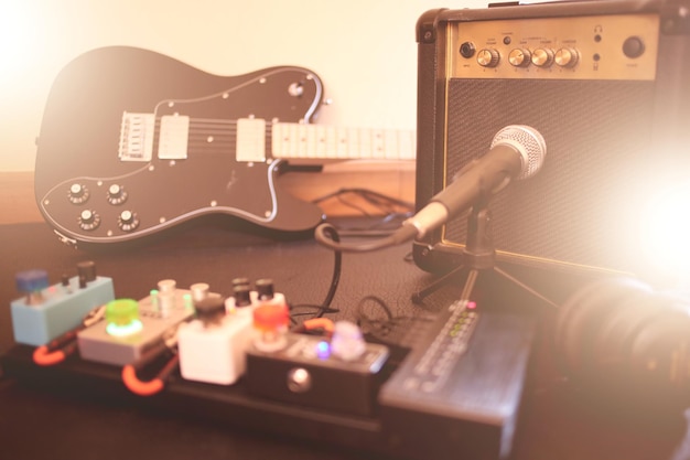 Foto chitarra elettrica con chitarra amplificatore sul palco di un concerto con calda illuminazione a bagliori