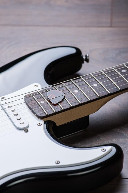 Electric guitar with mediator on a brown wooden floor