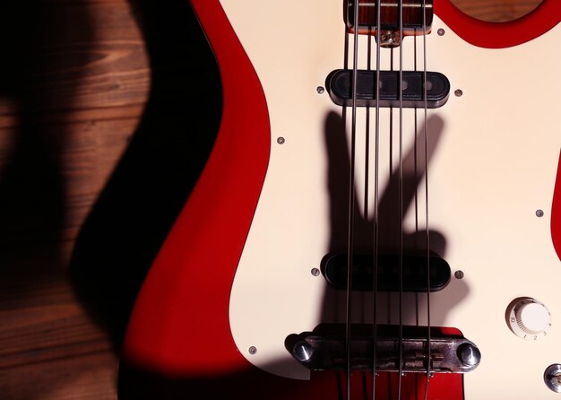 Electric guitar with shadow hand on wooden background