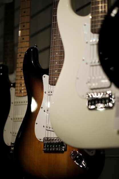 Electric guitars hang on the wall in a music store. vertical\
photo. close-up.