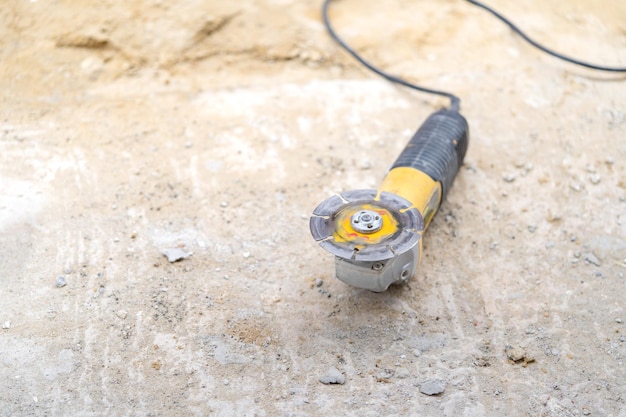 Electric hand held sawing machine is on the sand floor at contruction site