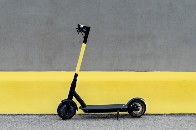 Electric kick scooter against wall. Ultimate grey and illuminating.