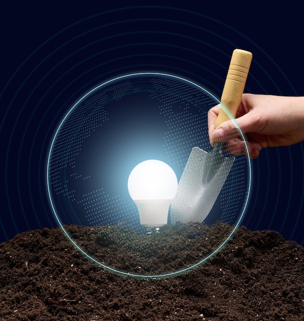 an electric lamp on the soil and a woman's hand holds a shovel. Concept of new ideas, start up