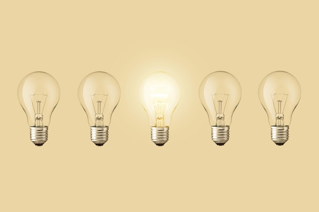 Electric light bulbs and one light bulb glows on a beige background Think differently Creative idea concept