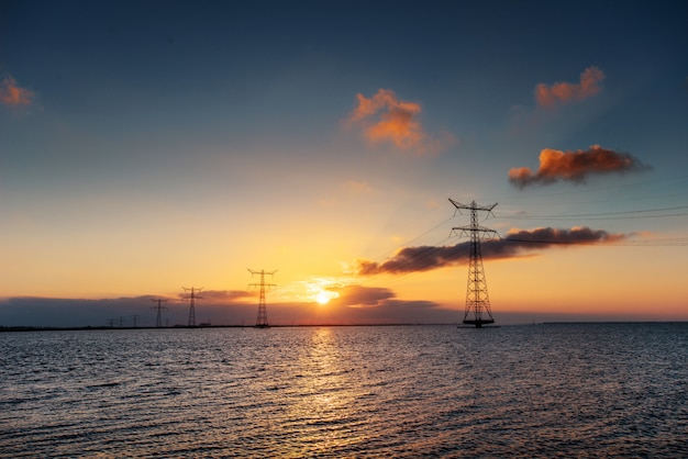 Linea elettrica sopra l'acqua durante un tramonto fantastico