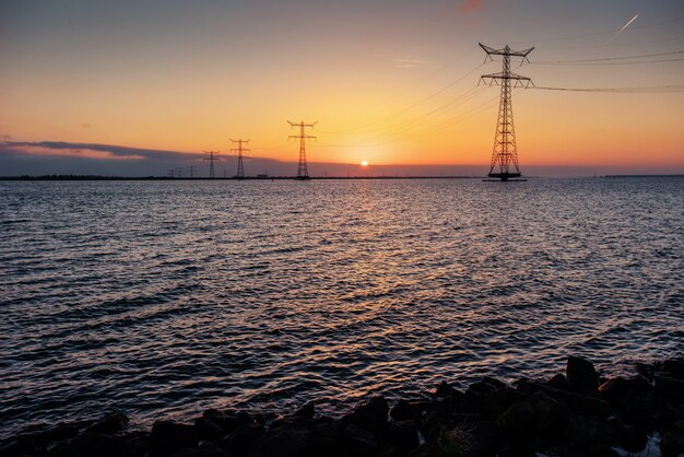 Linea elettrica sopra l'acqua durante un tramonto fantastico