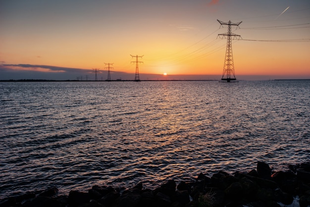 Electric line above water during a fantastic sunset