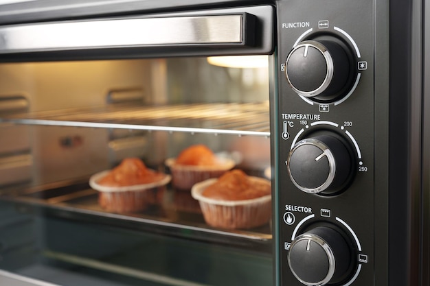 Electric mini oven and baked hot muffins close up