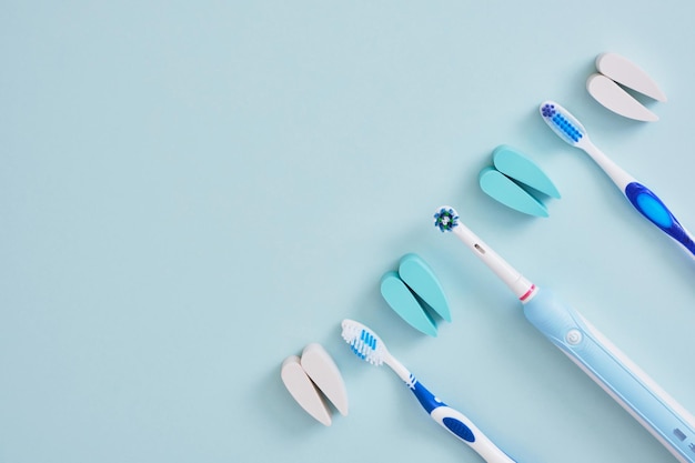 Electric and plastic toothbrushes on a blue background which\
brushes are more effective in cleaning the oral cavity