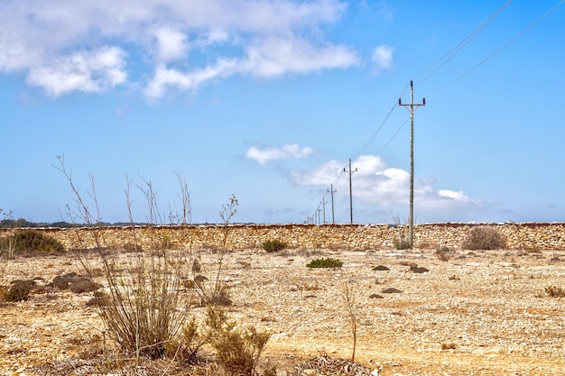Electric poles in a line crossing desert land