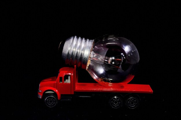 Electric Power Concept Red Truck and Light Bulb on a Black Background