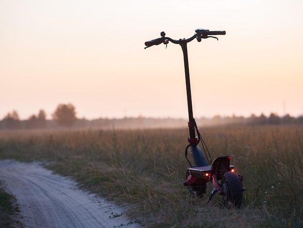 Electric scooter on a sandy country road copy space sunrise