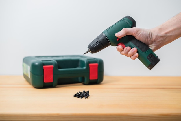 Electric screwdriver in a man's hand on a white background as well as on a tree background