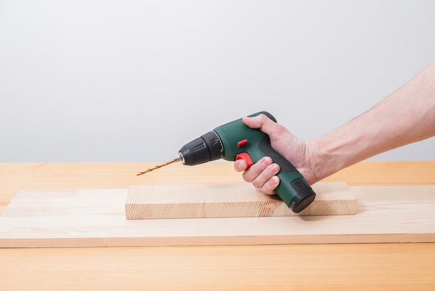 Electric screwdriver in a man's hand on a white background as well as on a tree background