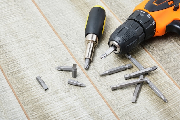 Electric screwdriver, self-tapping screws, screwdriver bits, tool box on a wooden surface copy space