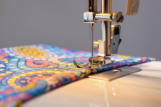 Электрическая швейная машина Деталь лапки для игольной пластины на цветной ткани, готовой к работе рядом