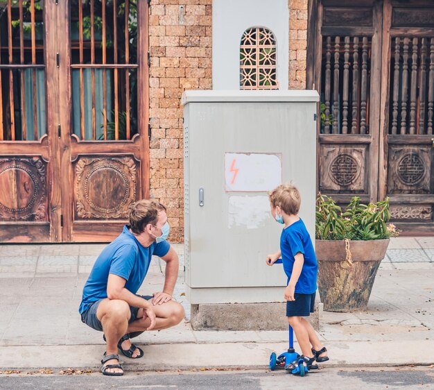 Electric shield high voltage switches father care of son safety\
dad explain child rules contact electrical installations devices\
wear covid blue face mask children education danger security\
concept