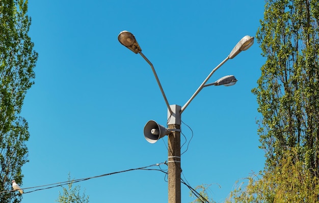 夏の晴れた日にポールのクローズアップにある電気街路照明ランタンと拡声器スピーカー