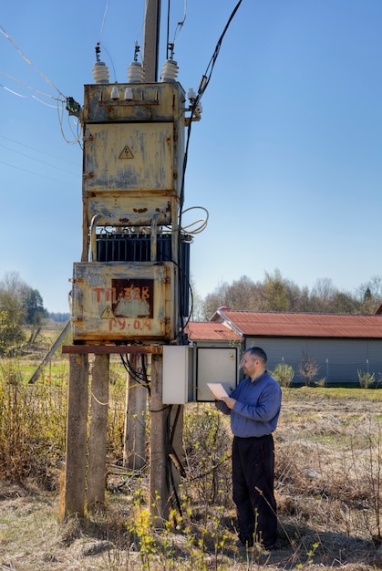 Electric substation, electrician engineer Technician reading electricity counter to check consumption.