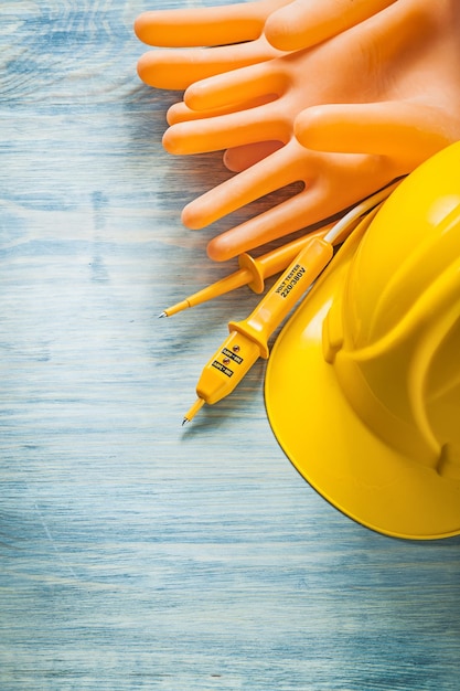 Electric tester dielectric gloves hard hat on wooden board electricity concept.