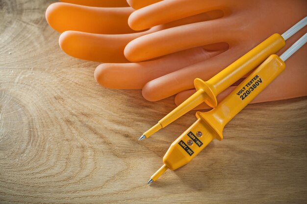 Electric tester dielectric gloves on wooden board.