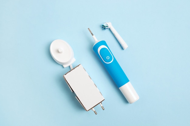 electric toothbrush and accessories on a blue background  charger and replaceable nozzle