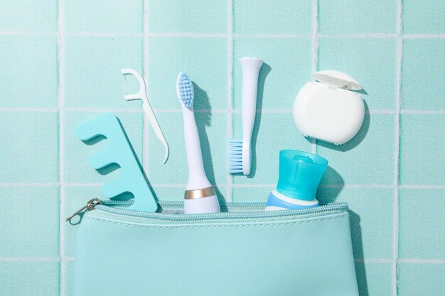 Electric toothbrush and cosmetic bag on blue background top view